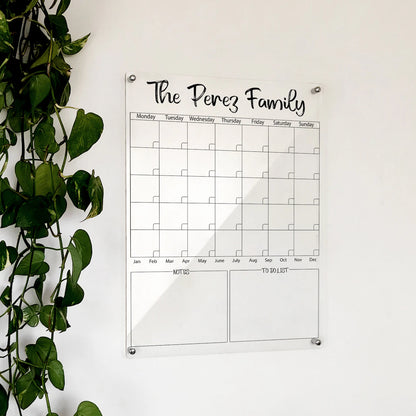 Personalized clear acrylic 'The Perez Family' monthly calendar with notes and to-do list, mounted by a plant
