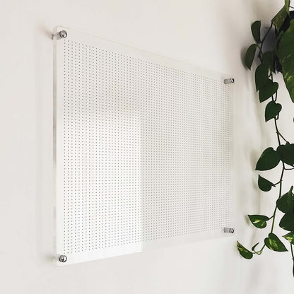 Angled close-up of the clear acrylic dot-grid planner board showing silver standoff hardware and edge