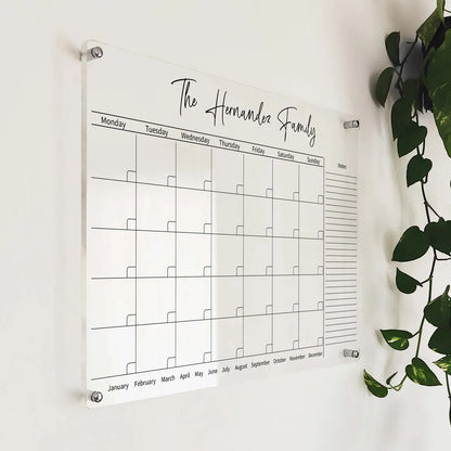 Angled close-up of 'The Hernandez Family' acrylic horizontal calendar mounted beside a hanging plant
