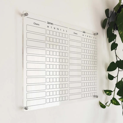 Personalized clear acrylic chore chart for two children (James and Julie) with weekday checkboxes, angled view
