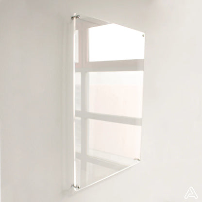 Blank clear acrylic dry-erase board mounted on a white wall with silver standoff hardware, angled view