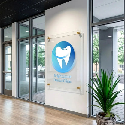 Clear acrylic dental clinic sign mounted beside glass entrance doors in a hallway view